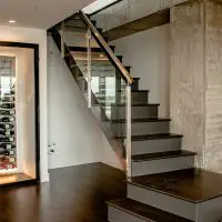 This glass and wood modern staircase nicely frames the wine closet.