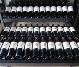 sliding metal wine rack with shelf inside a cabinet and bottles lying flat