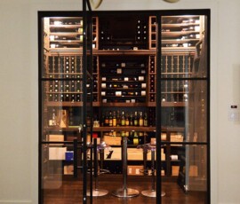 The finished doorway to the residential custom wine room in Dallas. Iron door flanked by glass window panes open up into the new wine room.