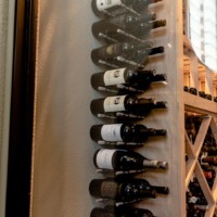 Metal corner wine rack with wine bottles.